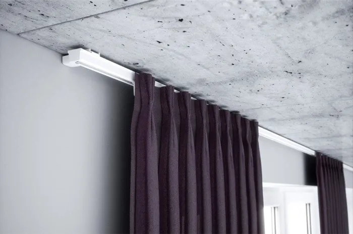 Фрагмент темной шторы на алюминиевом потолочном пороге