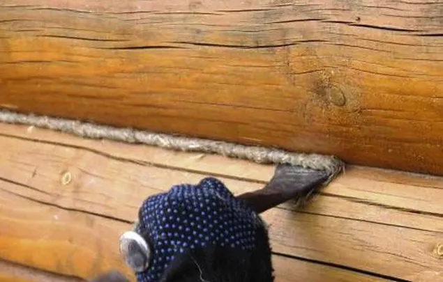 На фото – так производится конопатка венцов бревенчатого дома