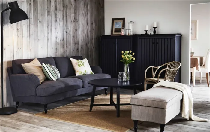 Темно-серый диван в интерьере со светлым пуфиком